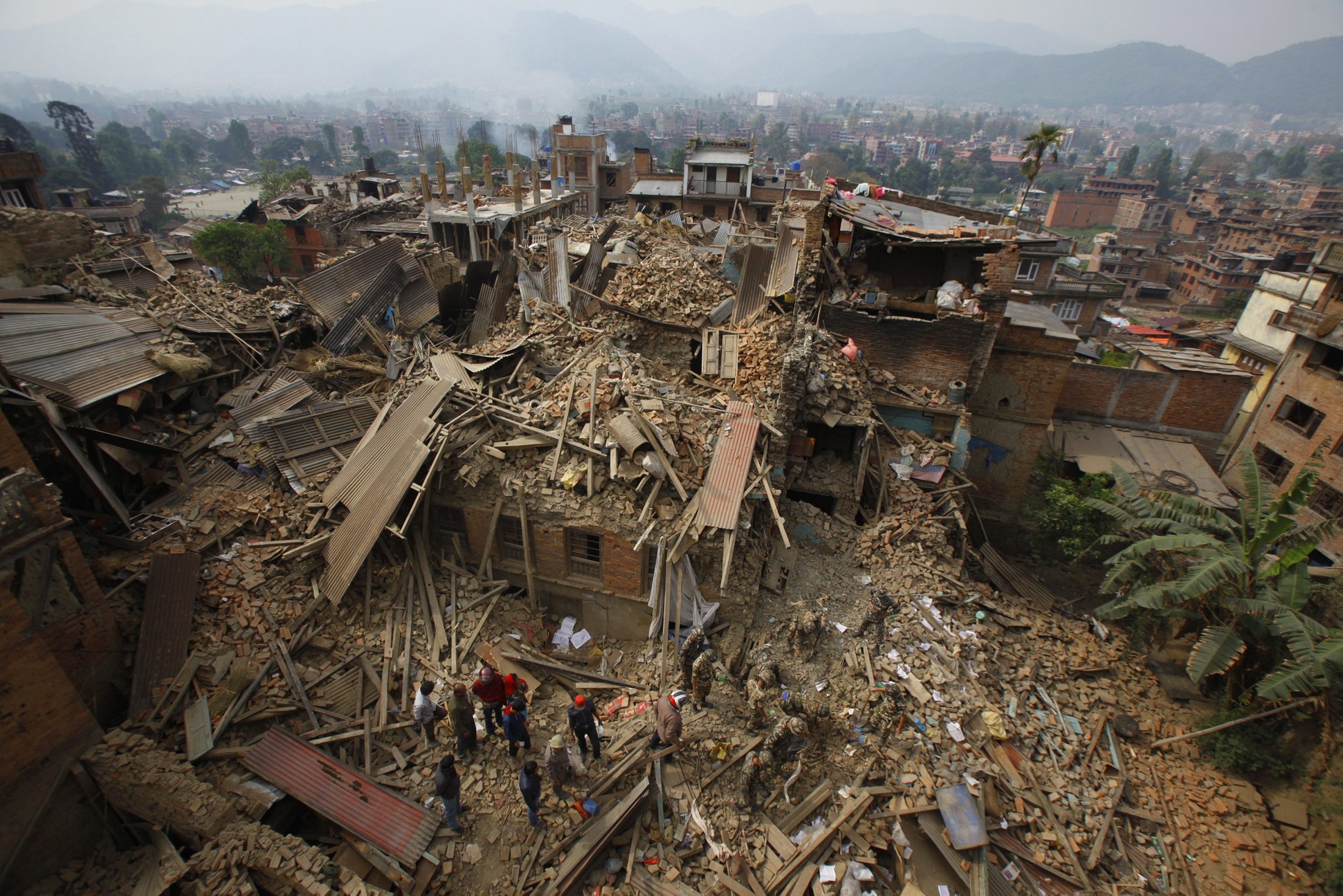 Rescue workers remove debris as they search for victims of earthquake in Bhaktapur near Kathmandu, Nepal, Sunday, April 26, 2015. A strong magnitude earthquake shook Nepal's capital and the densely populated Kathmandu Valley before noon Saturday, causing extensive damage with toppled walls and collapsed buildings, officials said. (AP Photo/Niranjan Shrestha)