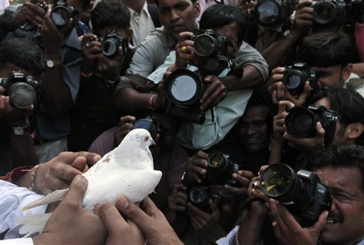 Photographers take pictures of volunteers of Hindu and Muslim organizations releasing a white pigeon, symbol of peace ahead of the Ayodhya verdict, in Mumbai, India, Wednesday, Sept. 29, 2010. The Allahabad High Court is scheduled to rule Thursday in the 60-year-old case on whether the site in the town of Ayodhya should be given to the Hindu community to build a temple to the god Rama or returned to the Muslim community to rebuild the 16th-century Babri Mosque that was razed by Hindu hard-liners in 1992. (AP Photo/Rajanish Kakade)