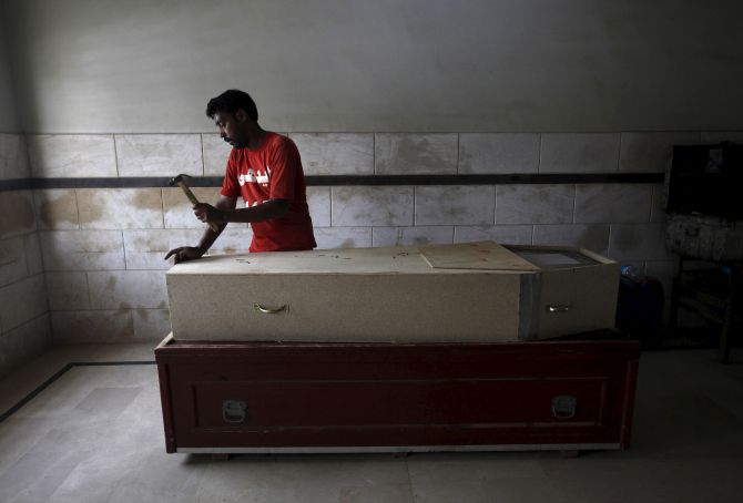 A volunteer prepares a coffin of a deceased who died due to an intense heat wave, before handing over to relatives, at Edhi Foundation morgue in Karachi, Pakistan, June 22, 2015. An intense heat wave killed more than 120 people over the weekend in Pakistan's southern city of Karachi, officials said on Monday, as the electricity grid crashed during the first days of the Muslim holy month of Ramadan. REUTERS/Akhtar Soomro - RTX1HK8V