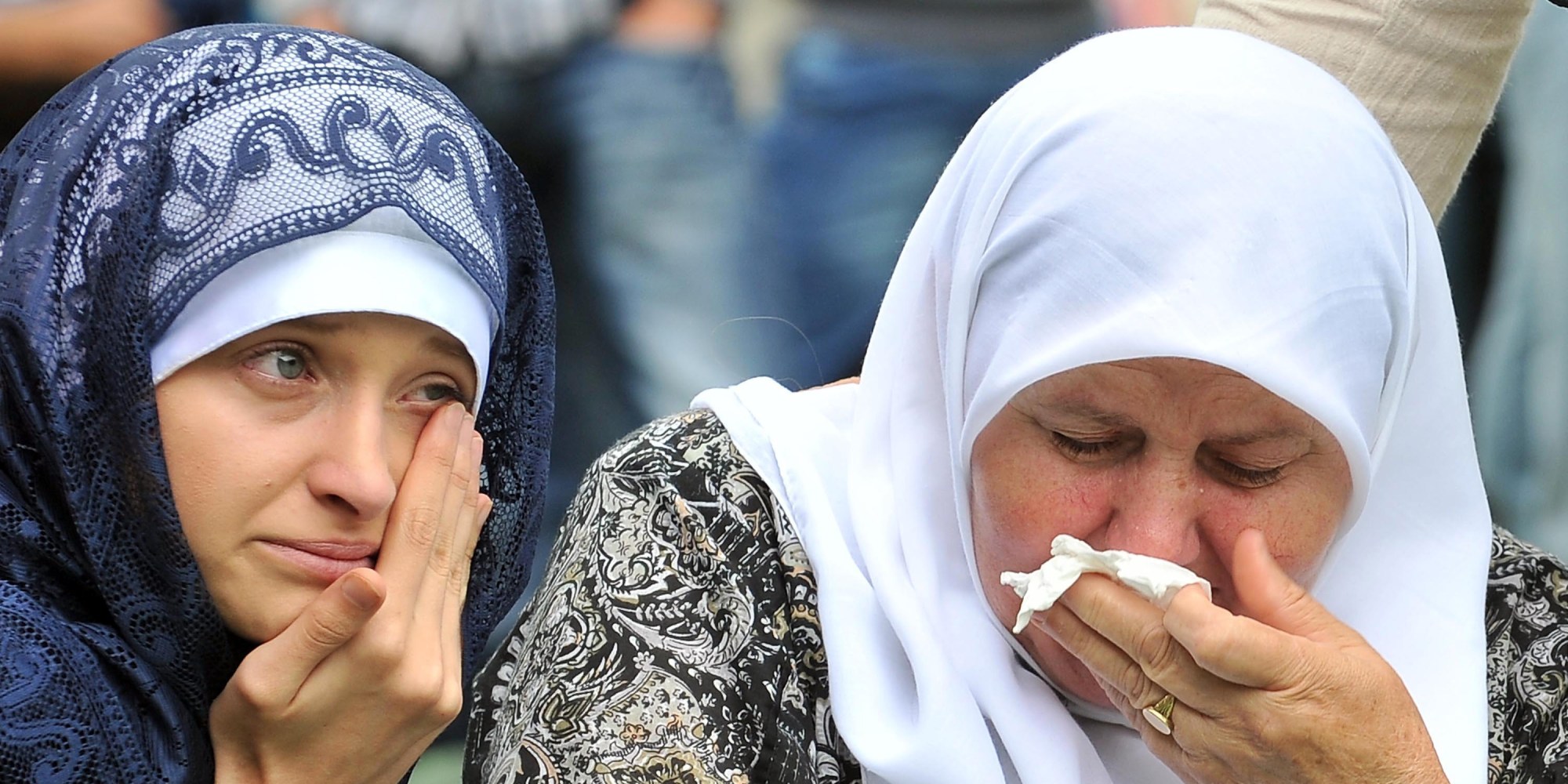 Bosnian Muslim women, cry in front of the coffin of a relative, layed out among others at the Srebrenica-Potocari Genocide Memorial cemetery in the village of Potocari near the eastern-Bosnian town of Srebrenica, on July 11, 2014. Several thousand people gathered on July 11 in Srebrenica for the 19th anniversary of the massacre of some 8,000 Muslim males by ethnic Serbs forces, Europe's worst atrocity since World War II. A total of 175 newly-identified massacre victims will be laid to rest after a commemoration ceremony held in Potocari, just outside the ill-fated Bosnian town. AFP PHOTO / ELVIS BARUKCIC (Photo credit should read ELVIS BARUKCIC/AFP/Getty Images)