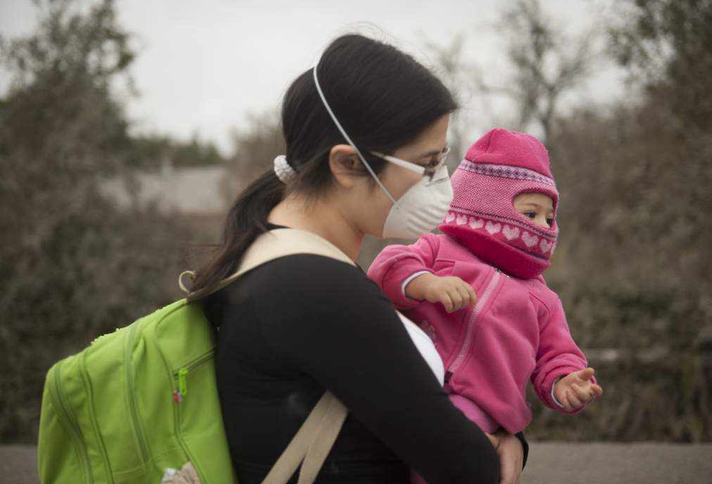 A woman carries her baby at La Ensenada, southern Chile, on April 26, 2015. A sleeping giant for more than 50 years, Calbuco sprang to life in spectacular bursts of ash and lava Wednesday and Thursday, forcing 6,500 people living nearby to evacuate and blanketed southern Chile in suffocating volcanic debris. AFP PHOTO/VLADIMIR RODAS (Photo credit should read VLADIMIR RODAS/AFP/Getty Images)