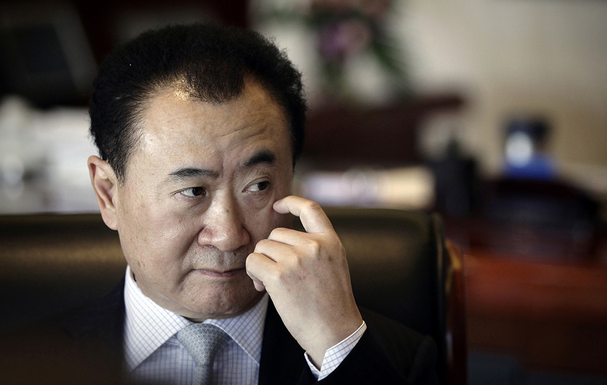 Wang Jianlin, chairman of Dalian Wanda Group, touches his face during an interview at his office in the company's headquarters in Beijing in this December 3, 2012 file photo. Chinese property developer Dalian Wanda Group says it can afford to spend as much as $5 billion every year to buy foreign firms or assets, underscoring the rising clout of the firm as it expands abroad. To match Interview CHINA-WANDA/ REUTERS/Suzie Wong/Files (CHINA - Tags: BUSINESS PROFILE HEADSHOT REAL ESTATE CONSTRUCTION)