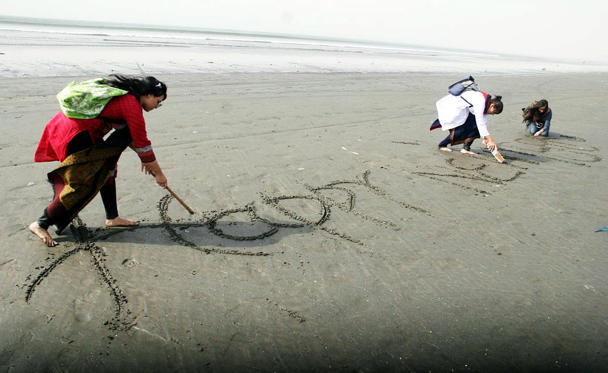 Girls write ‘New Year’ on sand at sea view in Karachi.–Online