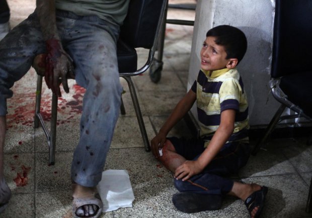 A Syrian boy cries as he looks at his wounded father