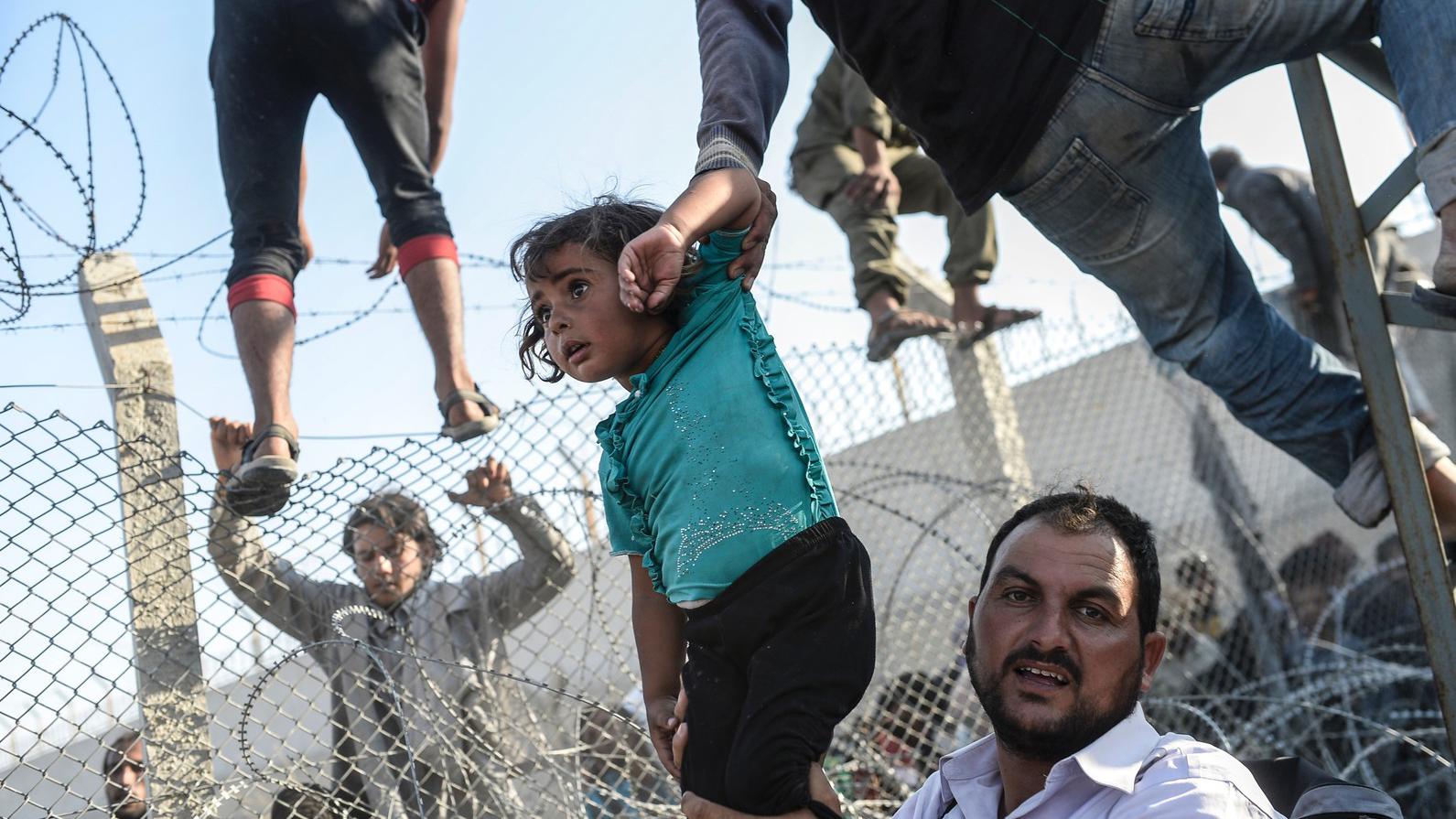 Syrian refugees climbing over border fences to enter Turkish territory illegally after fleeing their home.–AFP