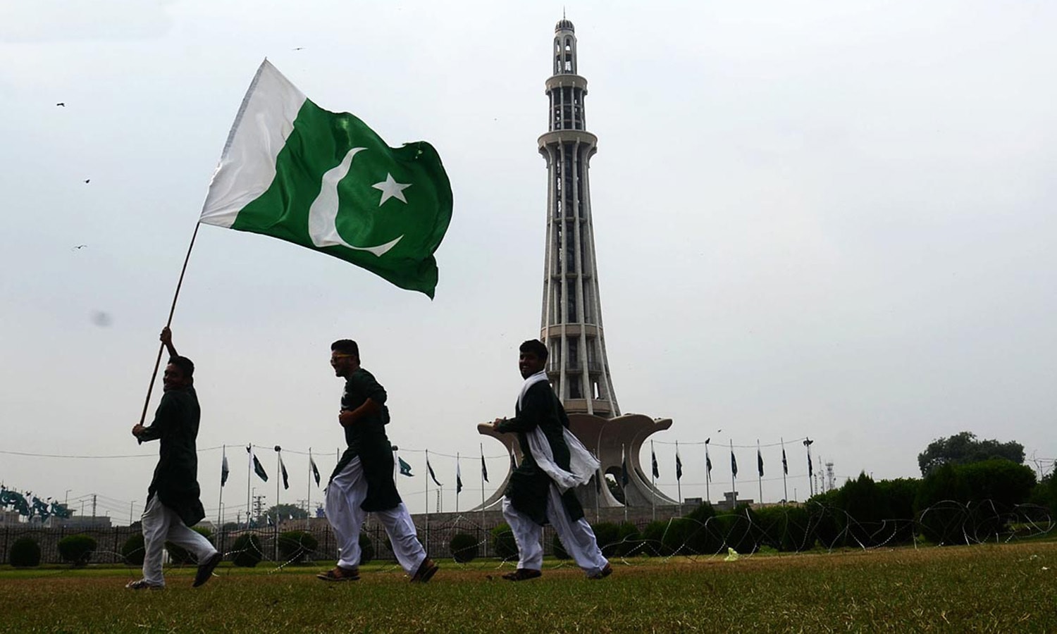 Px13-050 LAHORE: Aug13 - People holding national flag at Minar e Pakistan in connection to Independence Day, in Lahore. ONLINE PHOTO by Sajid Rana