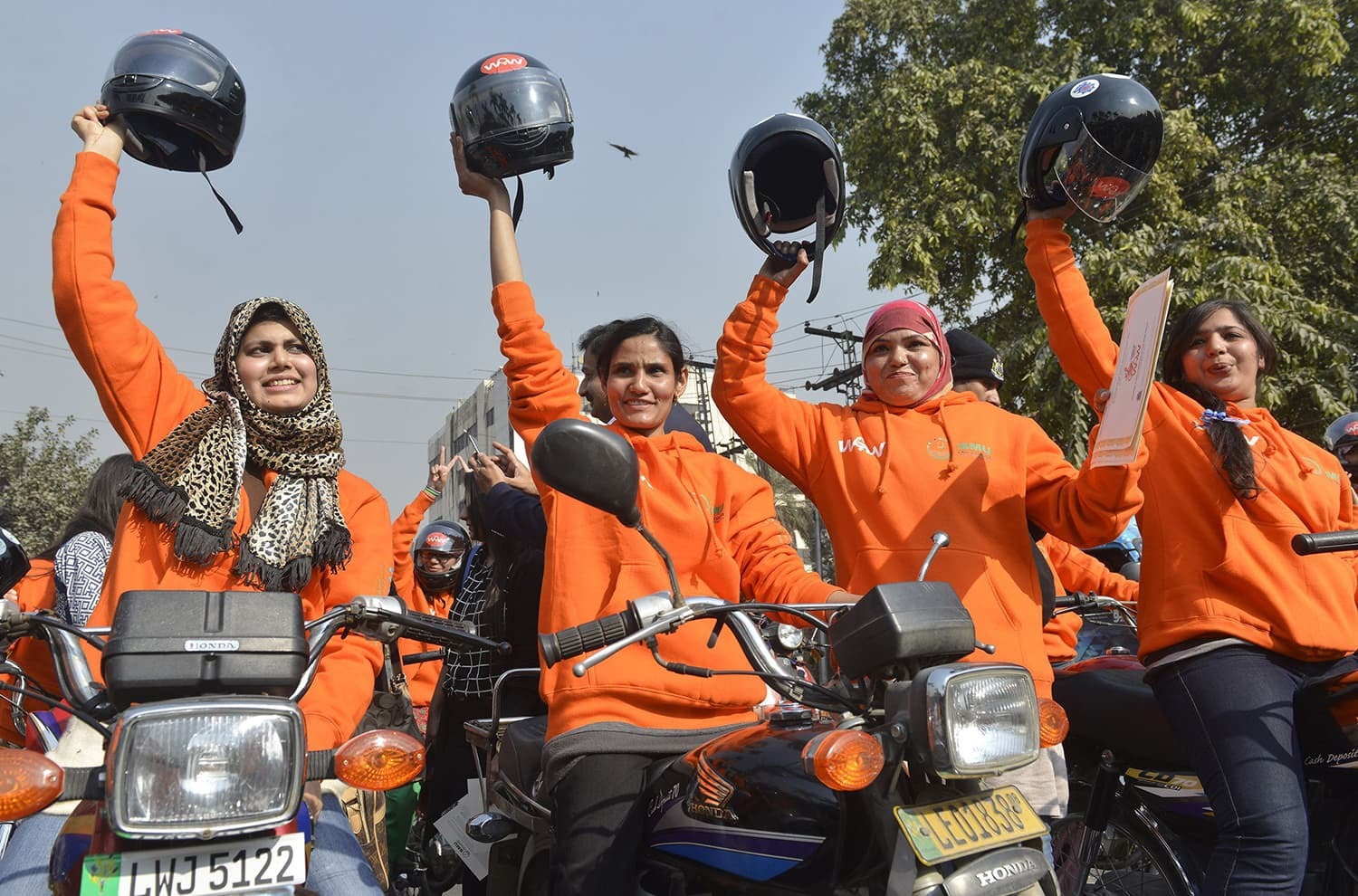 Women participants of Women on Wheels (WOW) raise their helmets at the start of a rally launching the Women on Wheels campaign in Lahore on January 10, 2016. AFP PHOTO / Arif ALI