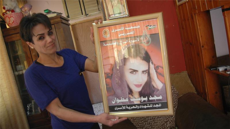 Nidal Atwan holds a poster of her daughter, Majd, after her arrest.–Al Jazeera
