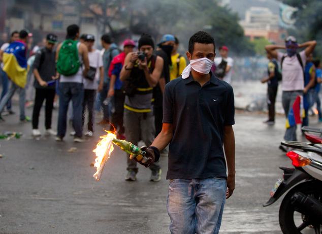 An opposition demonstrator prepares to throw a molotov cocktail at police after clashes broke out at a protest in Caracas, Venezuela, Thursday, Feb. 12, 2015. Venezuelans staged dueling marches to mark the anniversary of last year's bloody protest movement that resulted in more than 40 people being killed, including both government supporters and opponents. Dozens of protesters remain jailed, while the social issues they railed against last year- a faltering economy, widespread shortages and pervasive violent crime - have only gotten worse. (AP Photo/Fernando Llano)
