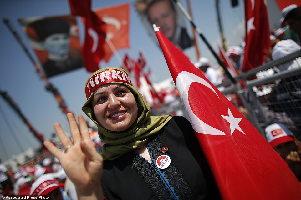 A Turkish woman waves as she holds a flag of her country during a Democracy and Martyrs' Rally in Istanbul, Sunday, Aug. 7, 2016. Crowds are gathering in Istanbul for a massive rally to mark the end of nightly democracy demonstrations following Turkey's abortive July 15 coup that killed over 270 people. (AP Photo/Emrah Gurel)